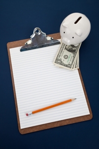 A piggy bank is positioned at the top of a clipboard, dispensing dollar bills.