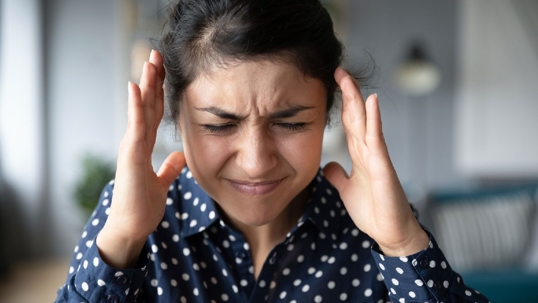 A woman clutches her head with a distressed expression.
