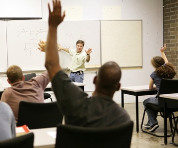 A classroom scene depicts a teacher at a whiteboard with several students raising hands.