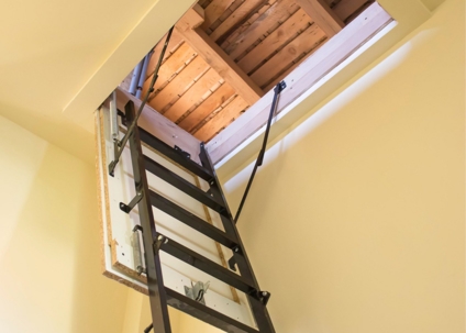 Partially extended attic ladder provides room access for maintenance.