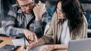 A couple reviews paperwork while sitting at a desk.