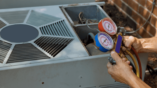 Here is a close-up of a person using pressure gauges to check an outdoor HVAC unit.