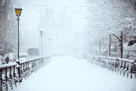 A snow-covered outdoor walkway is shown, with several benches and street lights visible.