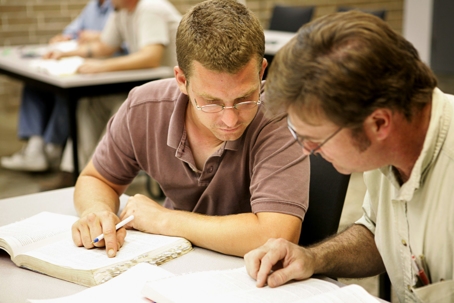 Two men are reviewing a book