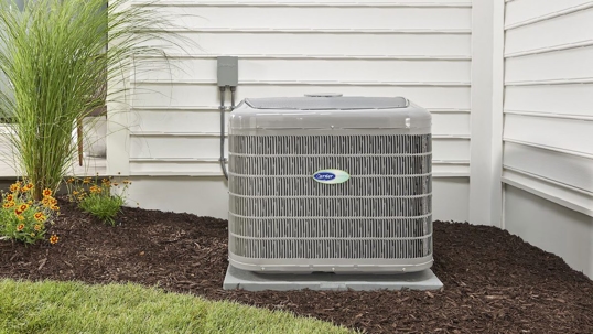 An outdoor AC unit is shown on a pad near a home's foundation, a Carrier brand logo is centered on it.